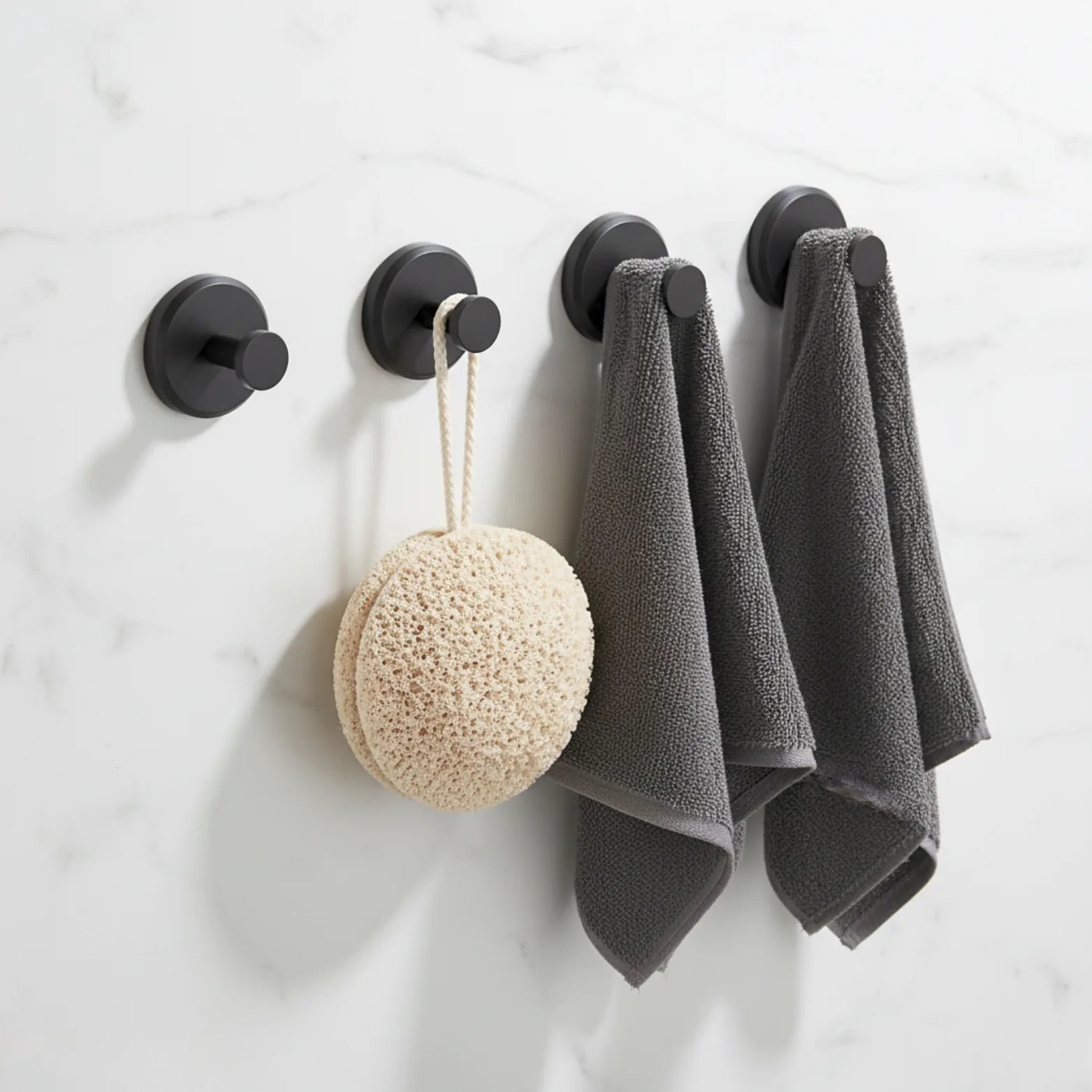Four Casorela suction cup hooks in matt black on a marble bathroom wall