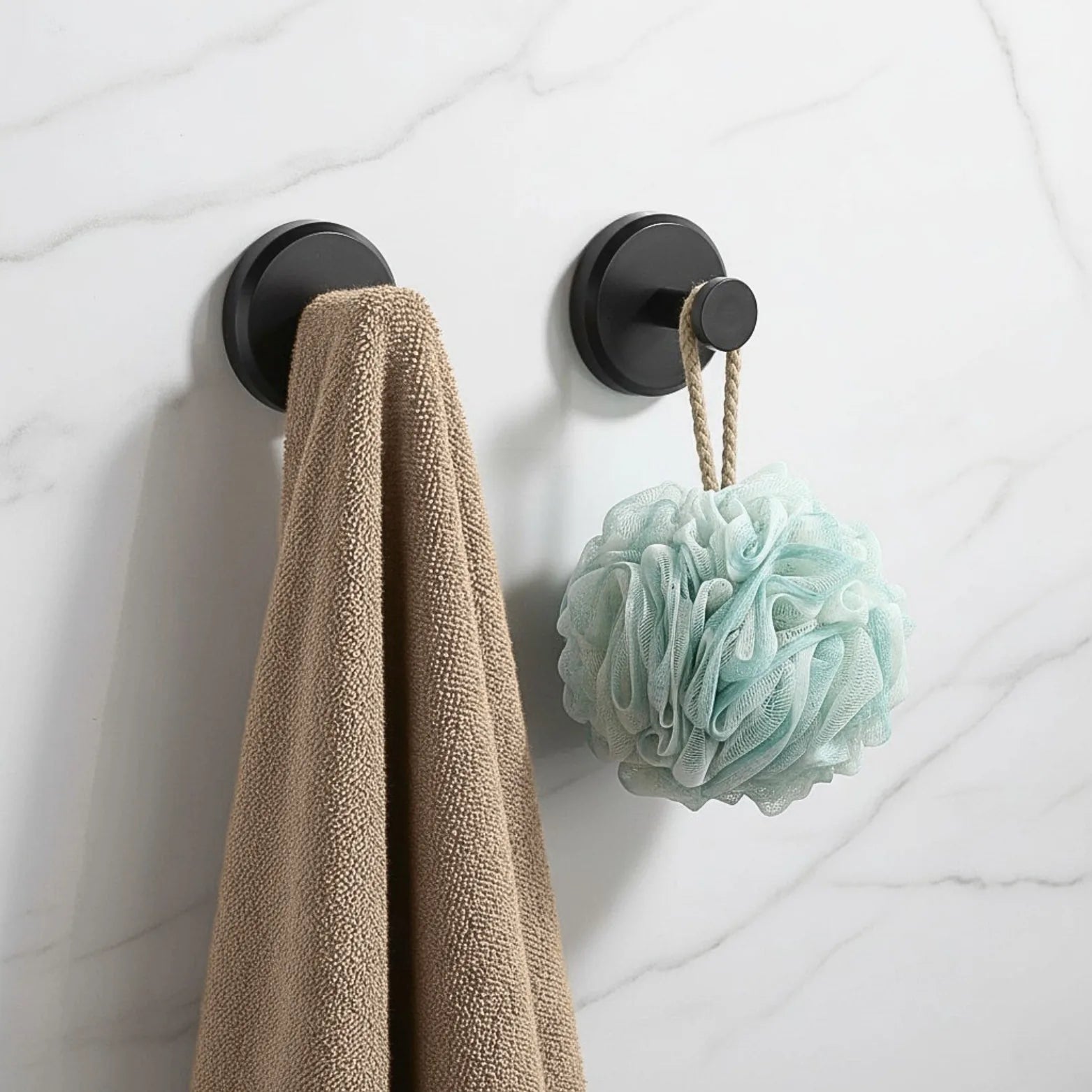 Hooks holding a towel and a shower puff on a tiled wall